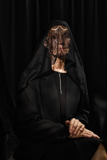 身穿蕾丝面纱的老年女性坐在黑色背景的摄影棚中图片下载