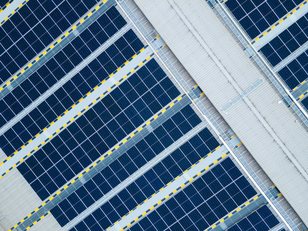 详细的照片提供了一个自上而下的航拍图像，太阳能电池板整齐地排列在工厂的屋顶上图片下载