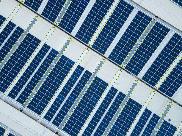 详细的照片提供了一个自上而下的航拍图像，太阳能电池板整齐地排列在工厂的屋顶上图片下载