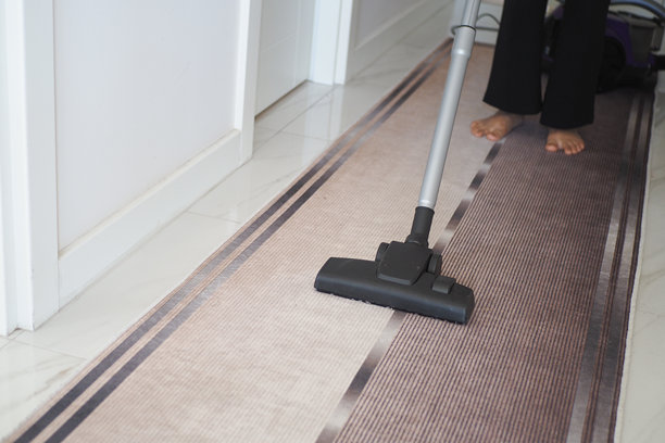 女性正在用吸尘器清洁地毯。图片下载