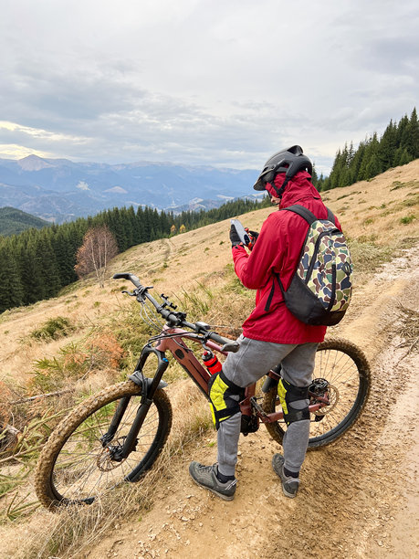 骑自行车的男子在户外骑电动自行车，享受美丽的山景。图片下载