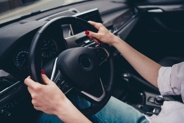 裁剪的照片，展示女性的手臂在城市街道上驾驶汽车，准备去度假。图片下载