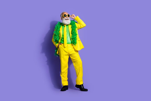 优雅迷人的老年男士穿着黄色西装，背景为紫色，留有空白空间的全身照片图片下载