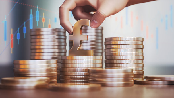 人手握住的英镑符号与金属硬币在金融背景下图片下载