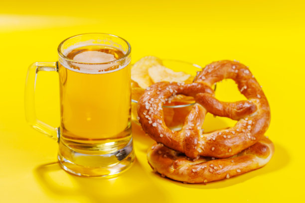 一张生动的照片，展示了一杯啤酒，周围是各种小吃和快餐。图片下载