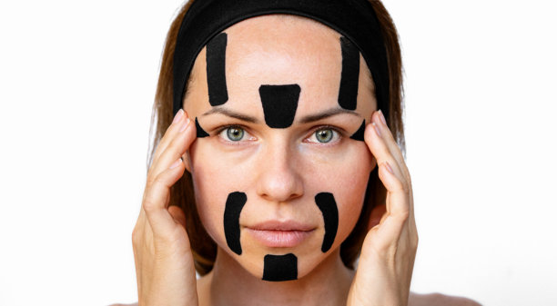 女性脸部特写照片，贴有黑色运动贴布。美容模特宣传面部运动贴布。图片下载