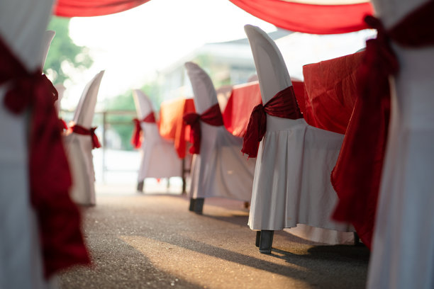 用白色布料覆盖的椅子，带有红色条纹装饰，适用于活动场合。婚礼活动。图片下载