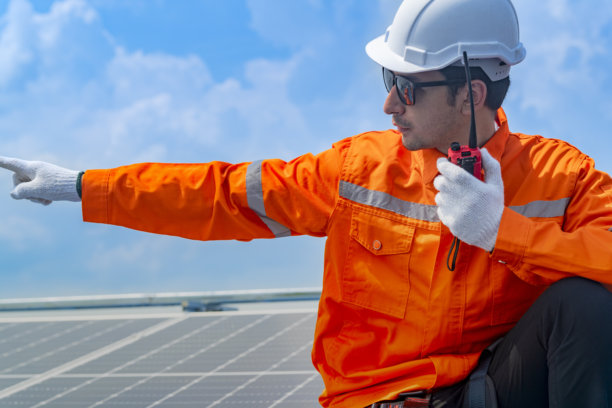 工人技术人员正在屋顶上安装太阳能电池板系统。男性技术人员在屋顶结构上行走，以检查光伏太阳能模块。图片下载