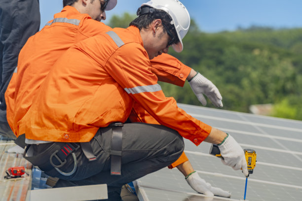 工人技术人员正在屋顶上安装太阳能光伏板系统。男性技术人员在屋顶结构上行走，以检查光伏太阳能模块。图片下载