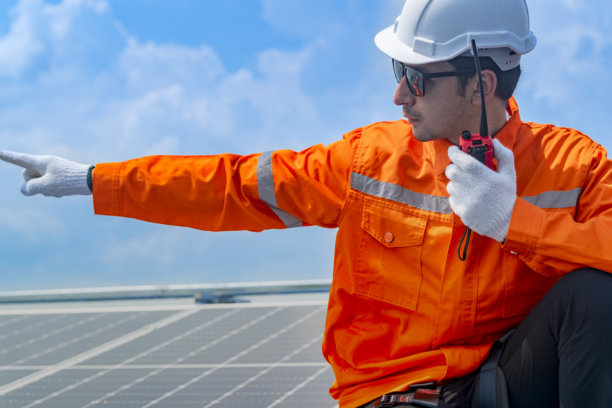 工人技术人员正在屋顶上安装太阳能光伏板系统。男性技术人员在屋顶结构上行走，以检查光伏太阳能模块。图片下载