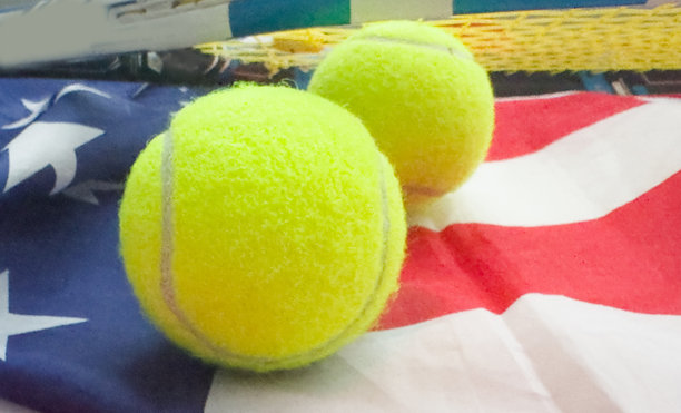 一把网球拍和一个网球放在美国国旗上。网球比赛概念图片下载