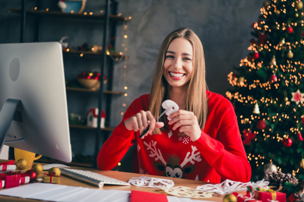 漂亮年轻女孩穿着圣诞服装，享受现代舒适的圣诞派对装饰，室内剪纸雪花的照片图片下载