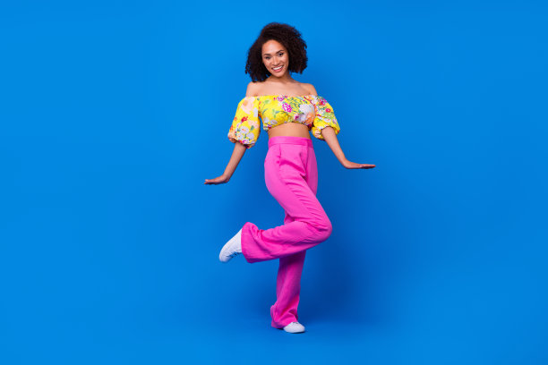 穿着黄色上衣的梦幻可爱女孩在蓝色背景下走动跳舞的全身照片图片下载