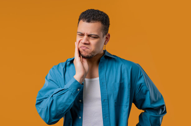 年轻男子牙痛，黄色背景。牙痛，牙科问题图片下载