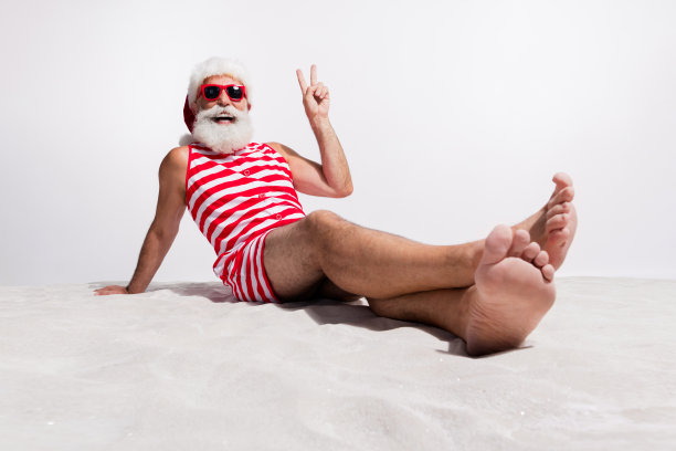 在海滩上享受假期的快乐圣诞老人照片，白色沙滩背景图片下载