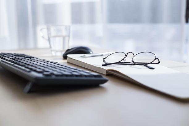 黑色键盘、鼠标、眼镜和笔记本放在家用办公室的木桌上图片下载