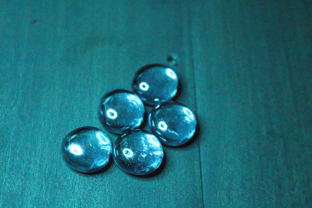 五颗透明玻璃宝石在青绿色背景上的抽象照片图片下载