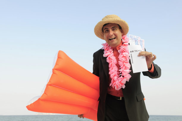 在海滩上手持机票和充气床垫的商人。有趣。图片下载