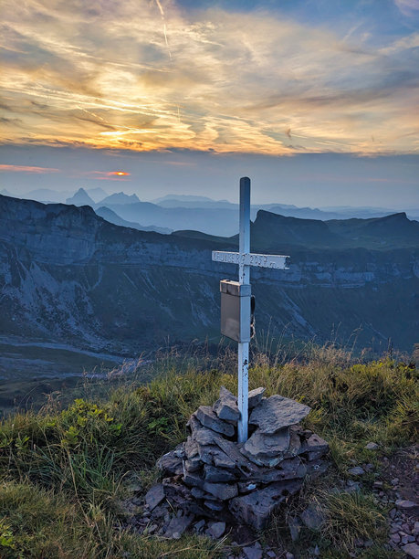 在穆奥塔塔尔的劳伊山上，云雾弥漫的日落时分，山顶十字架矗立，展现出瑞士山脉的美丽。高质量照片。图片下载
