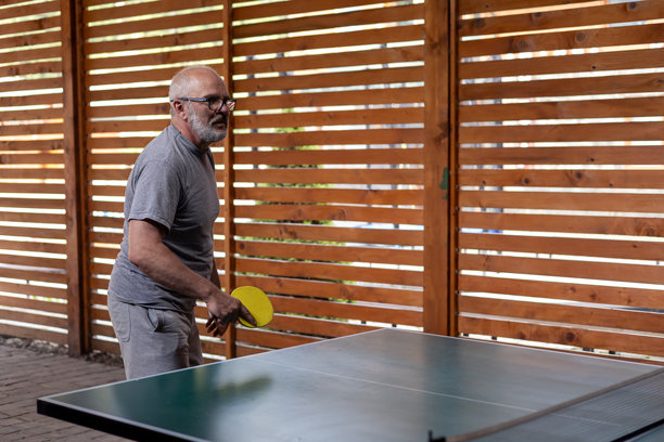 微笑的中年灰发男子在打乒乓球图片下载