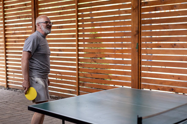微笑的中年灰发男子在打乒乓球图片下载
