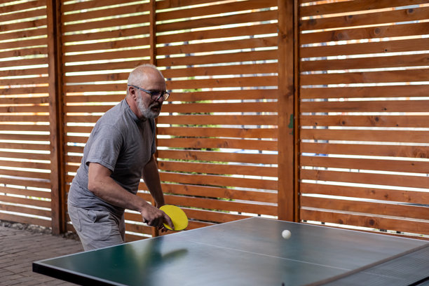 微笑的中年灰发男子在打乒乓球图片下载