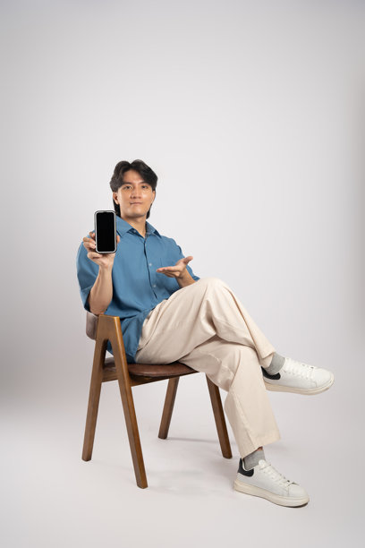 年轻亚洲商务男士坐在椅子上，背景为白色。图片下载