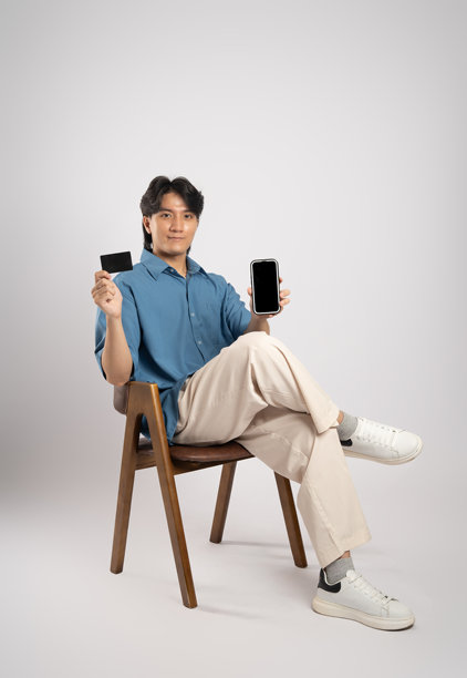 年轻亚洲商务男士坐在椅子上，背景为白色。图片下载