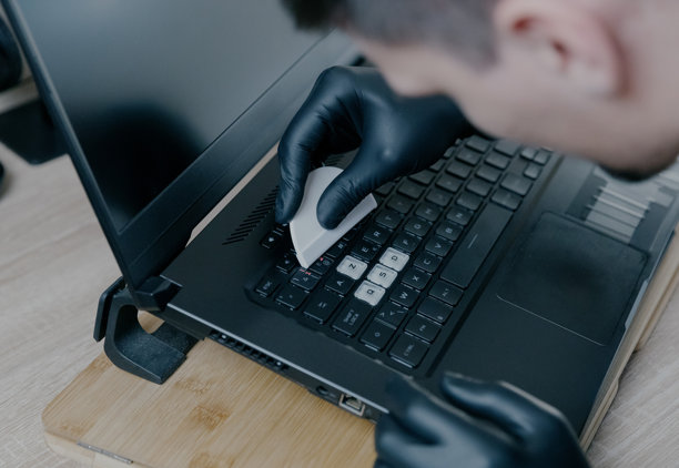 一个年轻人用特殊塑料将贴纸粘贴到笔记本电脑键盘上。图片下载