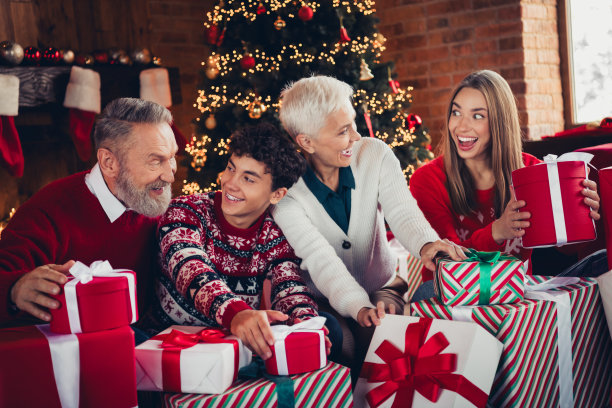 兴奋的家庭照片，祖母、祖父、孙子和孙女在室内抓住许多圣诞礼物。图片下载