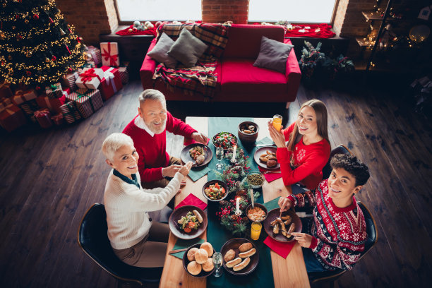 高角度视图的照片，大家庭聚在一起庆祝圣诞节，坐在室内公寓的餐桌旁。图片下载