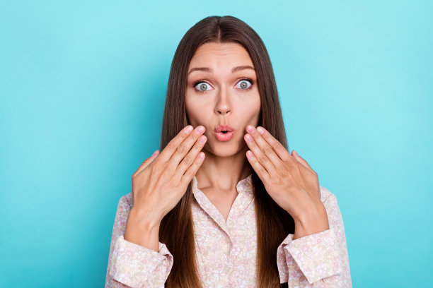 一位漂亮的惊恐女士用手触摸颧骨，因收到高价购物的坏消息而感到震惊，背景为青色。图片下载