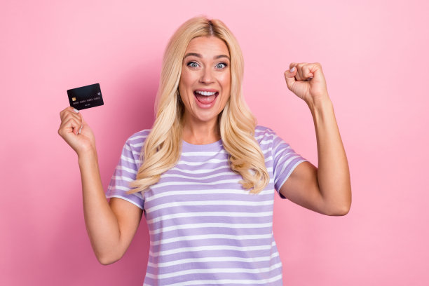 身穿紫色条纹T恤，握拳欢呼，手持银行卡，赢得彩票的快乐积极女人照片图片下载