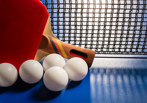 蓝色桌子上放着乒乓球拍和球，旁边有网。图片下载
