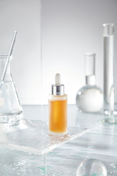 一个极简风格的照片模板，展示了一个姜黄黄色的精华滴管瓶、水滴、实验室玻璃器皿和一个玻璃球，背景为白色，非常适合用于护肤产品的广告。图片下载