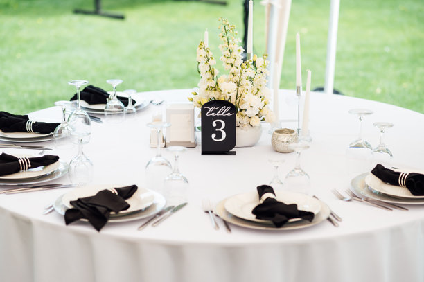 户外婚宴。桌子上摆放着白色餐盘和高档酒杯。图片下载