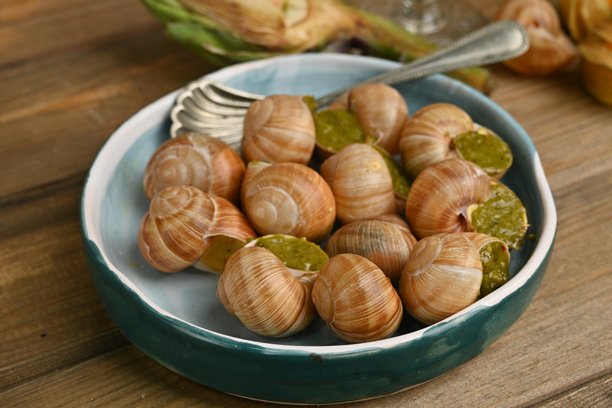 宏观蜗牛与香蒜酱的照片，上面是蜗牛配罗勒香蒜酱、帕尔马干酪和松子。图片下载