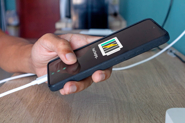 手握手机，同时从墙壁插座充电图片下载