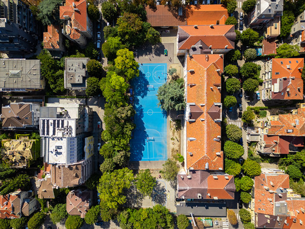 绿树和建筑环绕的校园篮球场和运动场鸟瞰：充满活力的城市空间，教育或城市规划视觉素材图片下载