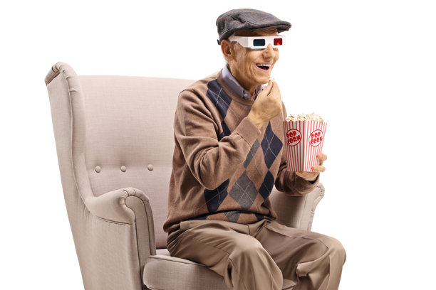 戴着3D眼镜的老人坐在扶手椅上吃爆米花图片下载