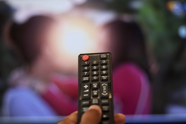 电视娱乐概念：手紧握电视遥控器图片下载
