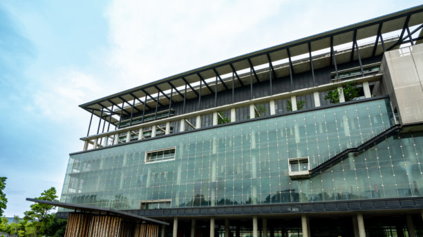 一张低角度拍摄的公寓综合体的图片，展示了太阳能反射器和垂直花园，背景是天空中的留白。图片下载