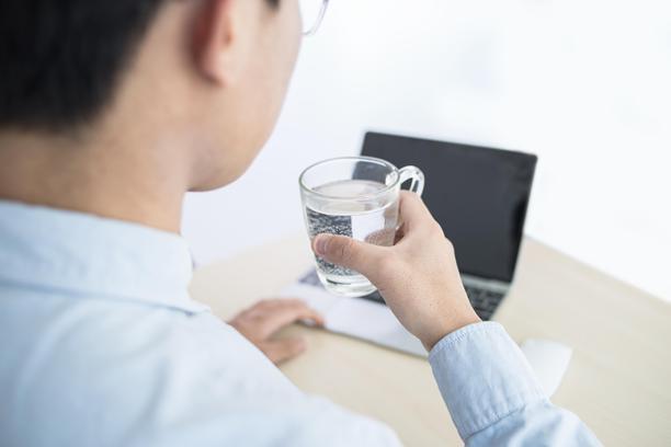 男人在使用笔记本电脑时喝水图片下载