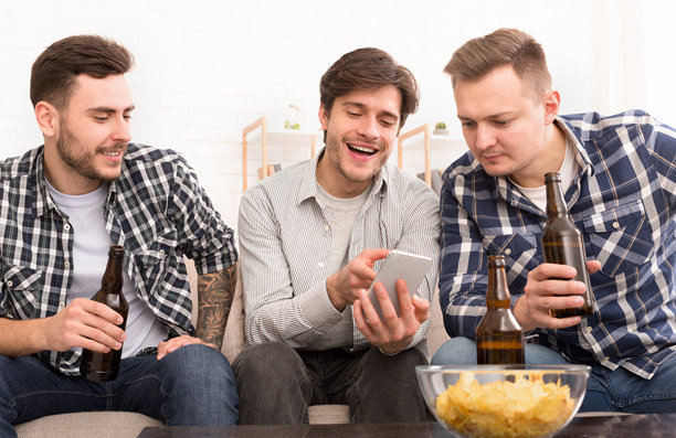 朋友们聚会。男人在手机上展示照片。图片下载