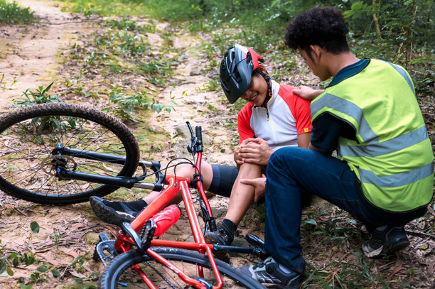 山地自行车事故，骑自行车者在自然公园的练习活动中摔倒并受伤，急需救助并接受急救人员的护理。图片下载