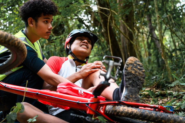 山地自行车事故，骑自行车者在自然公园的练习活动中摔倒并受伤，急需救助并接受急救人员的护理。图片下载