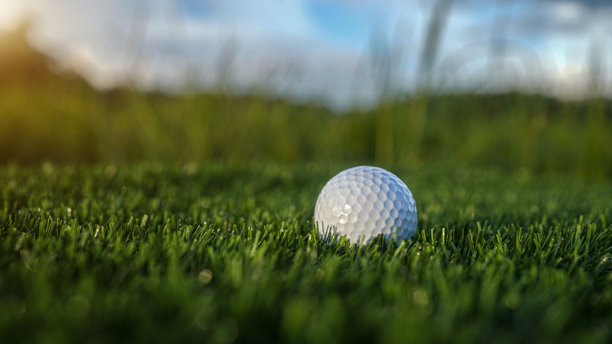 高尔夫球在美丽的高尔夫球场的绿草坪上，沐浴在晨光中。图片下载