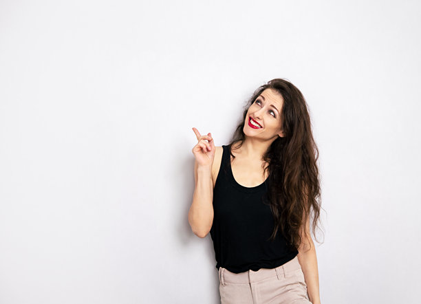妆容精致的快乐女子，身穿黑色休闲上衣，手指上方，展示创意图片下载