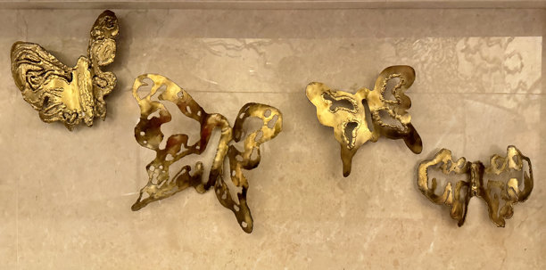 锻造和铸造的金色铁板形成蝴蝶的形状，贴在墙上。创意金属工艺品。图片下载