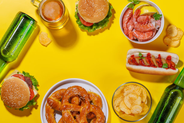 一张生动的照片，展示了一杯啤酒，周围是各种小吃和快餐。图片下载